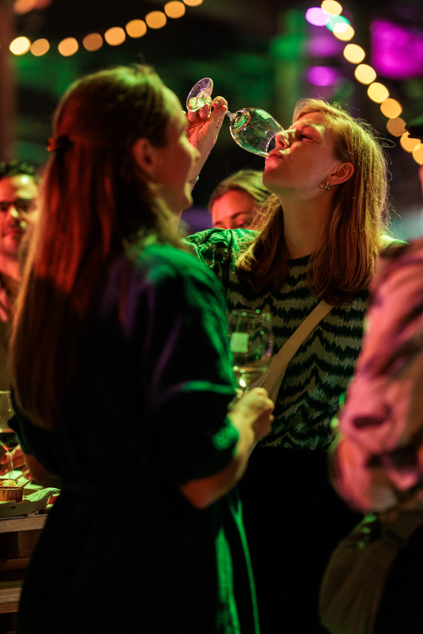 Twee vriendinnen proosten uitbundig met een glas wijn tijdens een festival